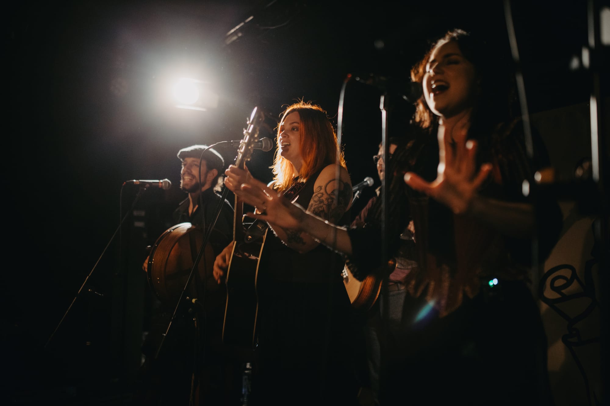 Three people on stage, one playing drum, one guitar and one singing.
